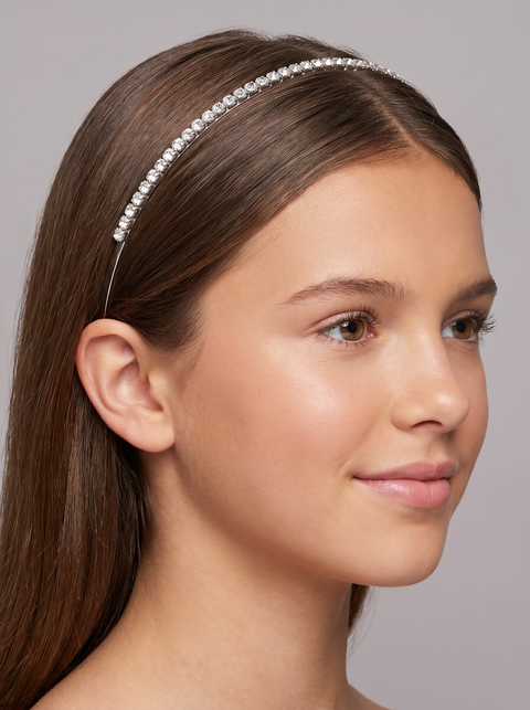 Young girl wearing a decorative headband against a neutral background