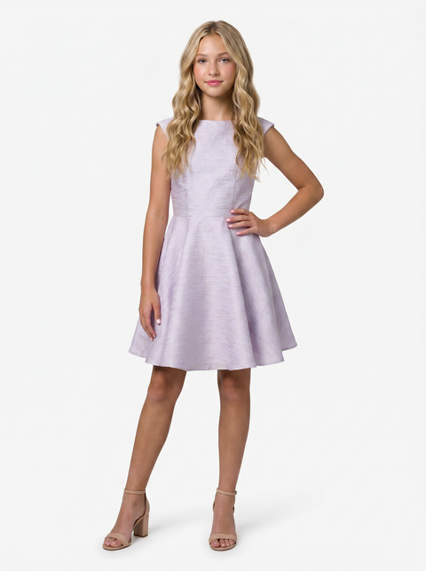 Young girl in a lilac cap sleeve dress with blonde hair in a nude shoe.
