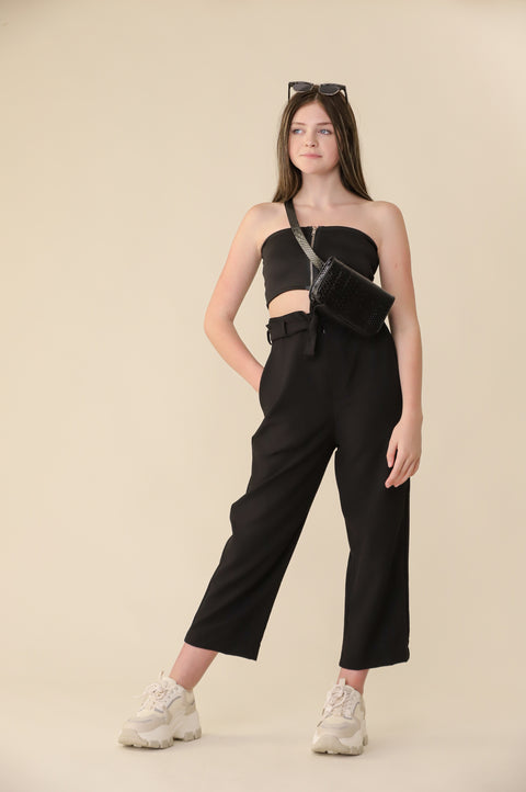 Woman wearing a black jumpsuit with cut-out design on a beige background