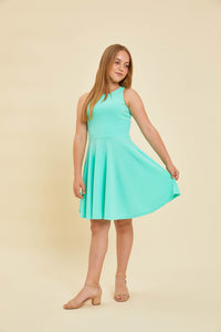 Blonde girl in a mint green racerback dress and nude shoe.