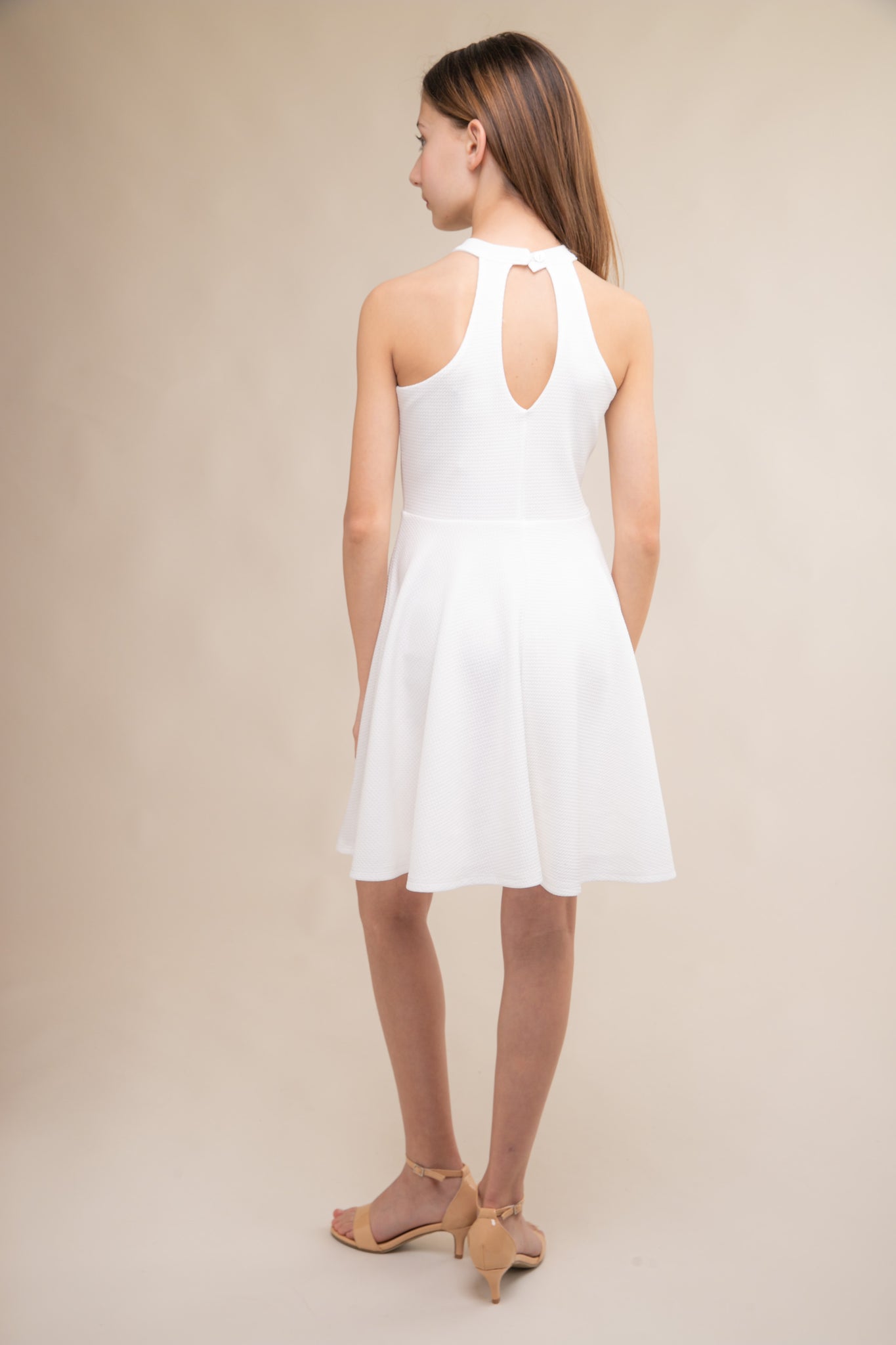 Halter dress in ivory features a full circle twirl skirt, open hole detailing in back and high waist line for a chic silhouette.
