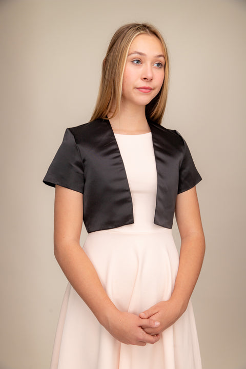 Blonde girl in a black satin bolero jacket worn over a dress.
