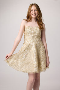 Red head in a gold beaded dress with nude shoe.
