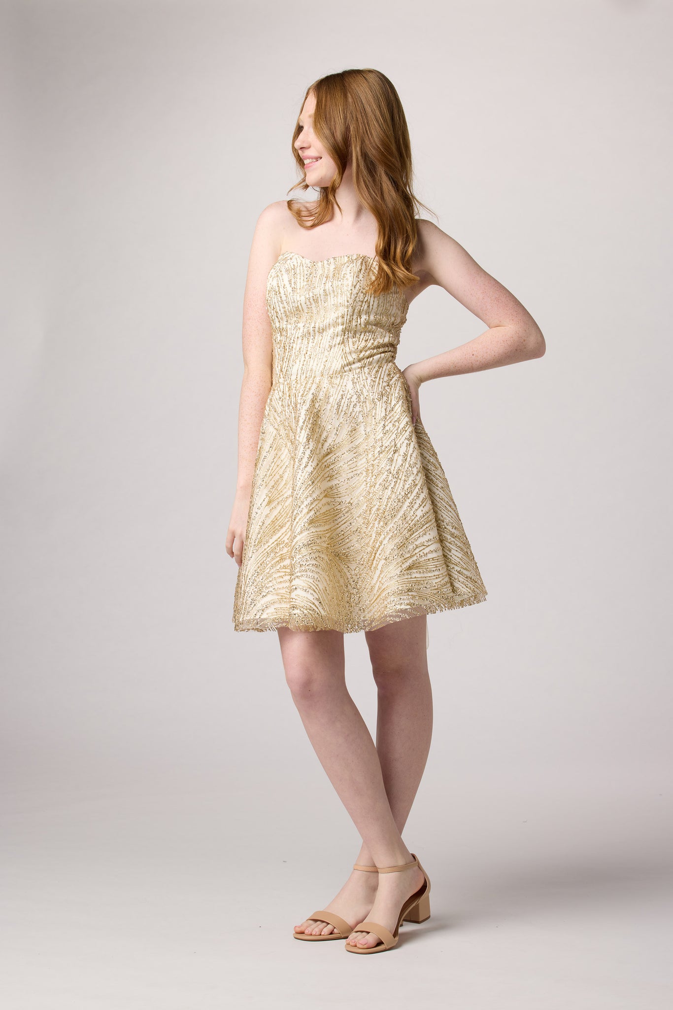 Red head in a gold beaded dress with nude shoe.