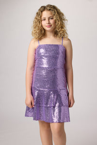 Blonde girl in an Un Deux Trois bow back sequin dress in lilac.