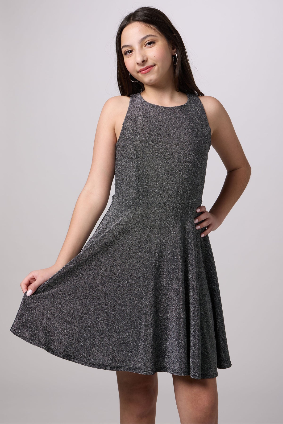 A woman modeling a sleeveless, knee-length gray knit dress with a flared skirt against a light gray studio background.
