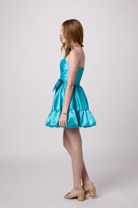 Red head in a turquoise bubble bow dress.