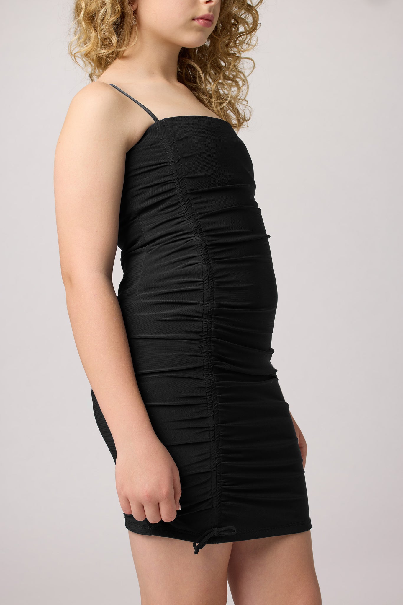 Blonde in an Un Deux Trois fitted ruched dress in black with nude heel.