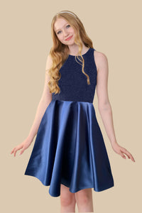 Blonde girl is a navy glitter bodice dress and satin skirt.