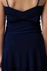 Blonde girl in a tiered bow back Un Deux Trois dress in navy.