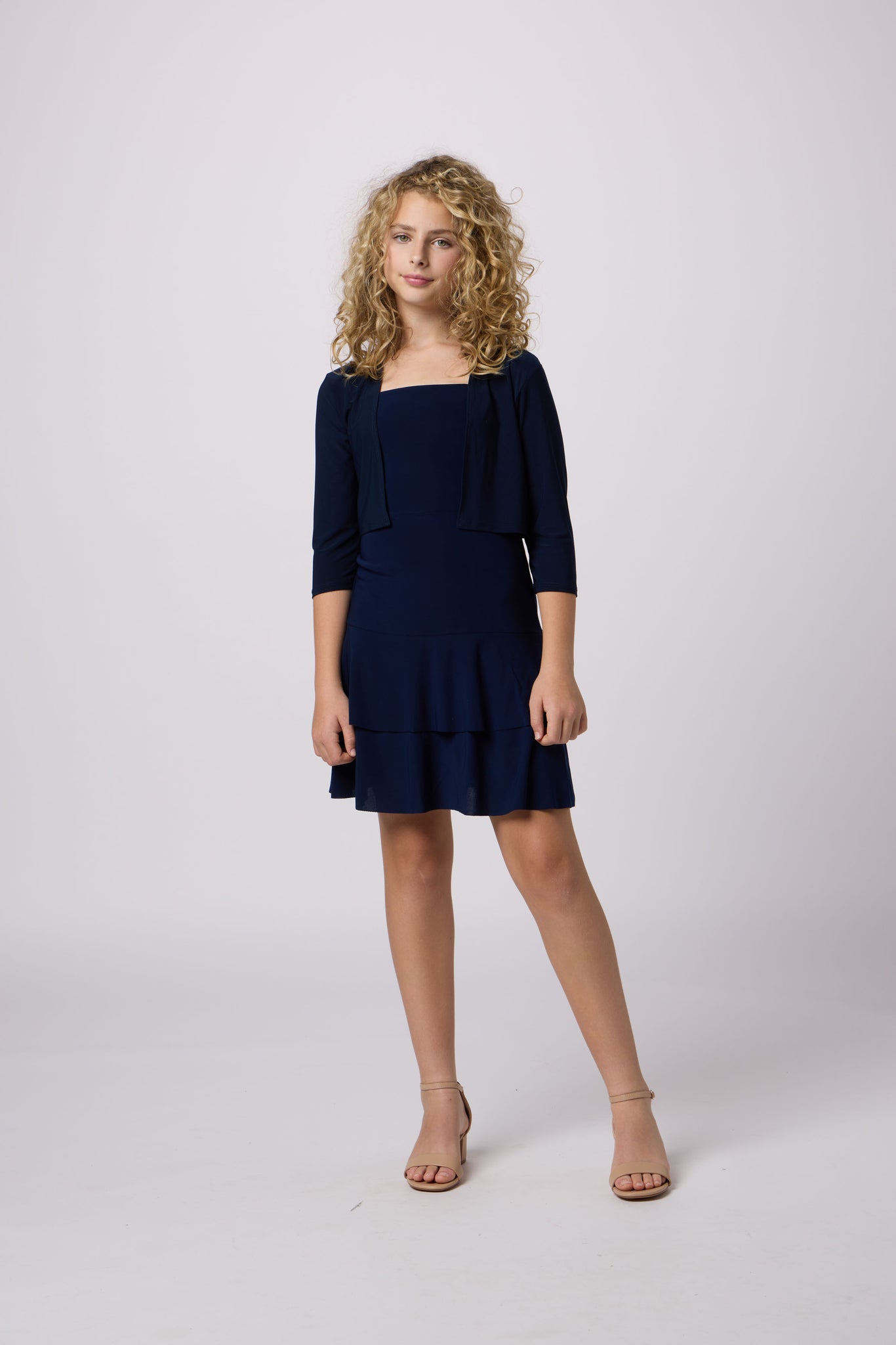 Blonde girl in a tiered bow back Un Deux Trois dress in navy.