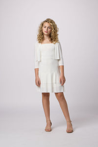 Blonde girl in an Un Deux Trois ivory bow back dress with tiered skirt.