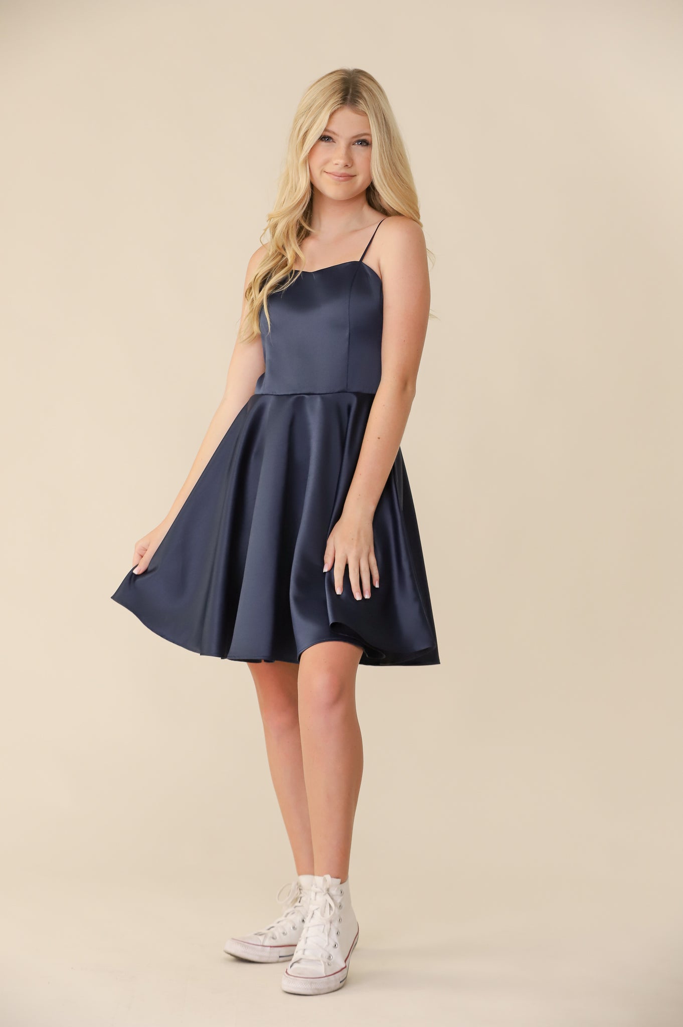 Blonde girl in a Un Deux Trois fit and flare navy satin dress.