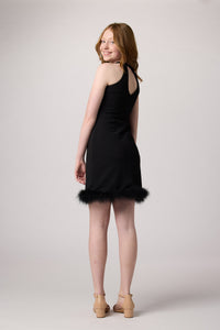 Red head girl in a black raglan halter dress with feathers.