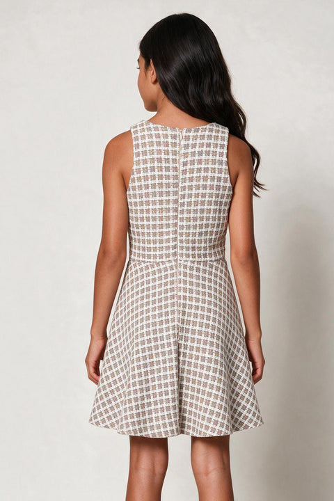 A sleeveless fit-and-flare dress with a beige and white geometric grid pattern, shown from the back on a child model against a light gray background.