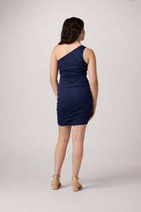 Brunette in an Un Deux Trois one shoulder fitted dress in navy glitter with nude heel.