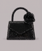 Black sequin handbag with a rose on a gray background