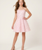 A young woman modeling a light pink sleeveless fit-and-flare dress with thin straps and a flared skirt, paired with nude high-heeled sandals, against a plain light beige studio background.