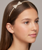 Young girl wearing a decorative headband with a bow on a neutral background