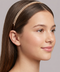 Woman wearing a gold headband against a neutral background