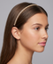 Woman wearing a gold headband against a gray background