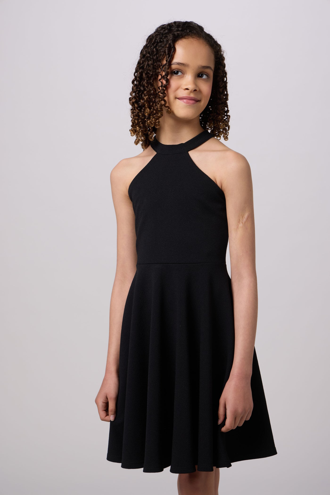 Young girl wearing a black dress against a plain background