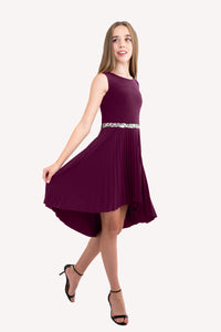 Blonde girl in a plum Un Deux Trois pleated high low dress with belt.