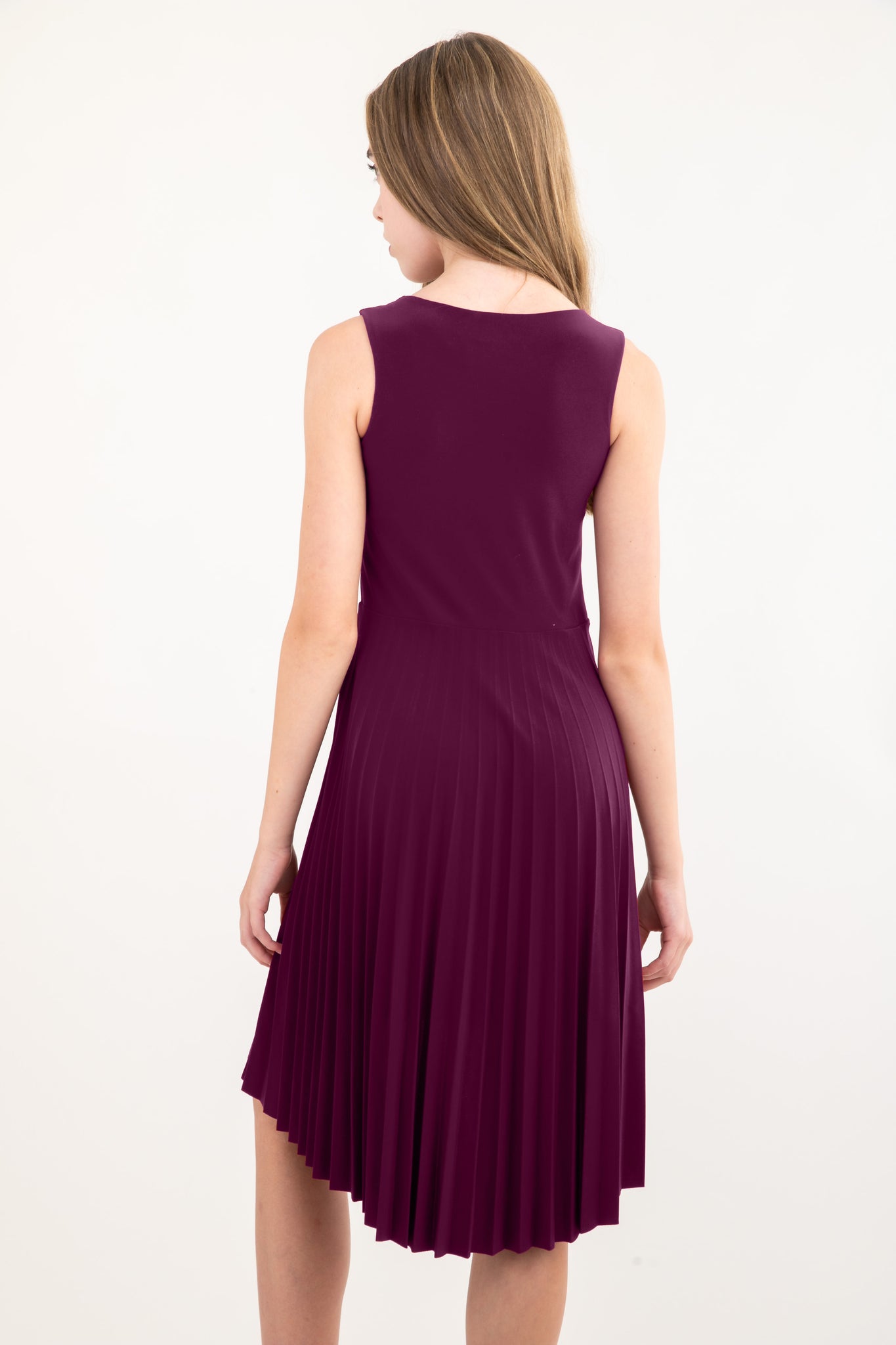 Blonde girl in a plum Un Deux Trois pleated high low dress with belt.