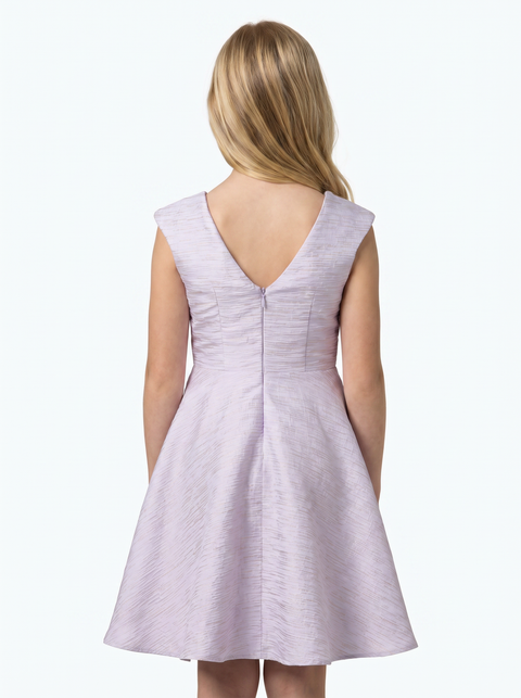 Young girl in a lilac cap sleeve dress with blonde hair in a nude shoe.