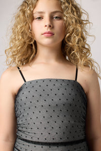 Blonde girl in an Un Deux Trois fitted ruched dress in black and silver glitter dot.