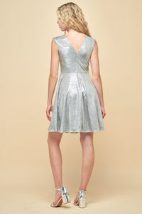 Blonde girl in a cap sleeve metallic fit and flare dress featured in silver with silver kitten heels.