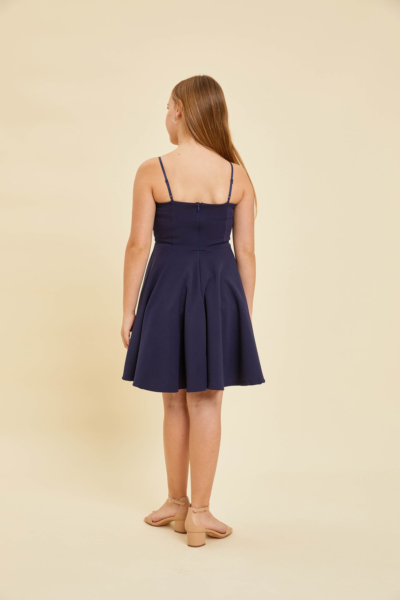 Blonde girl in a navy textured fit and flare dress with belt.