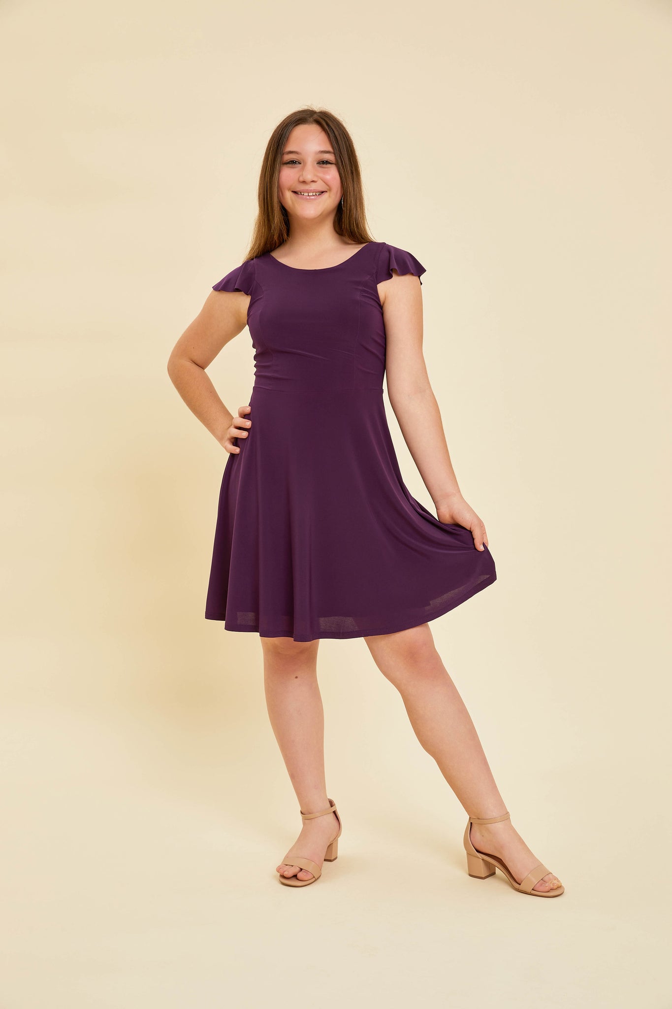 Blonde girl in a purple plum flutter sleeve dress with nude heel.Blonde girl in a purple plum flutter sleeve dress with nude heel.