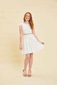 Red head in an ivory flutter sleeve dress and nude heel and belt.