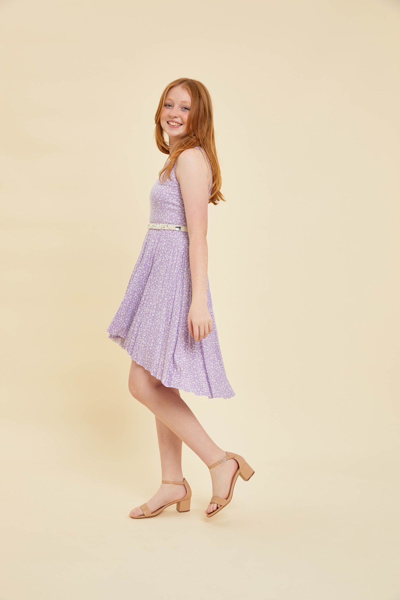 Red head in a lilac floral pleated dress with belt and nude shoe.