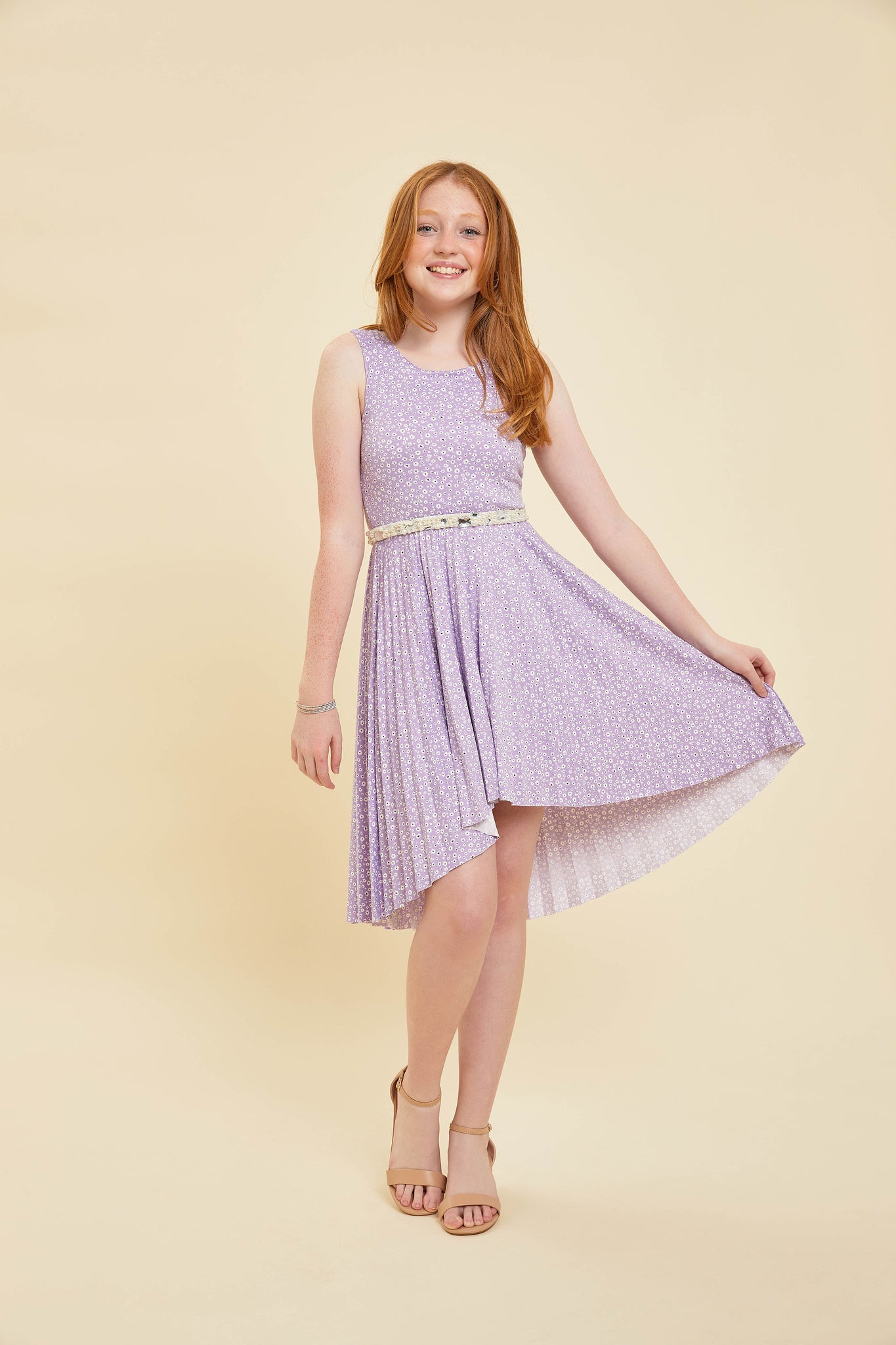Red head in a lilac floral pleated dress with belt and nude shoe.