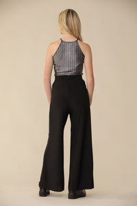 Blonde girl in a silver top with black wide leg pant and boot.