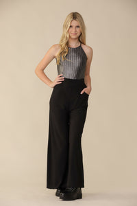 Blonde girl in a silver top with black wide leg pant and boot.