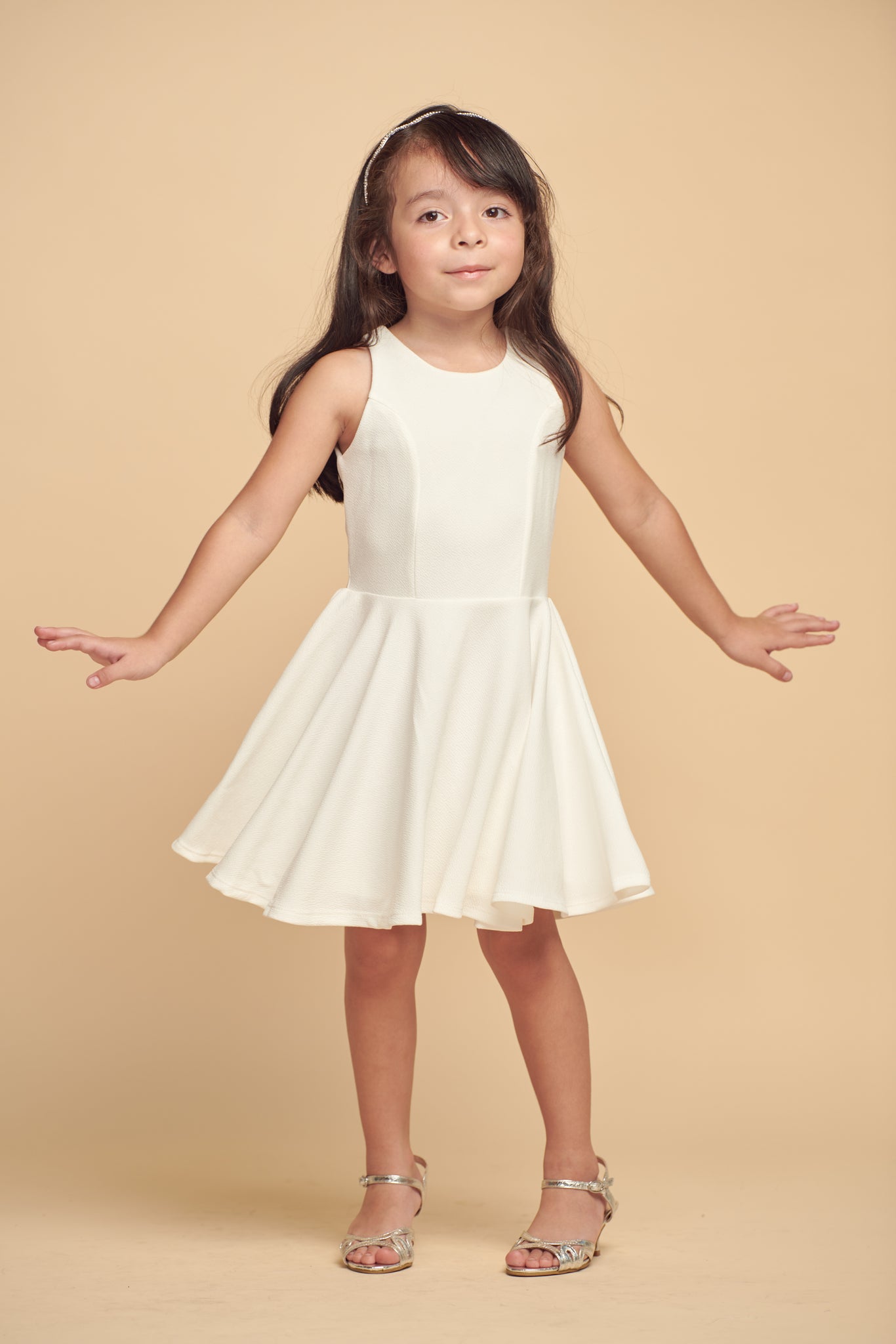 The tank style sleeve textured fit and flare dress is shown in ivory with high neck line, racerback detailing and dart bodice for a chic and sophisticated look. This dress can be worn to a more conservative special occasion event like cotillion, graduation, or religious service like a bat mitzvah service or church ceremony.