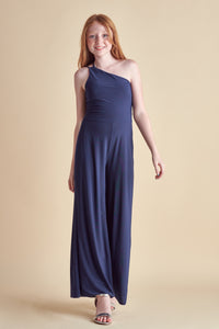 Blonde girl in a one shoulder, navy wide leg jumpsuit with silver heel.