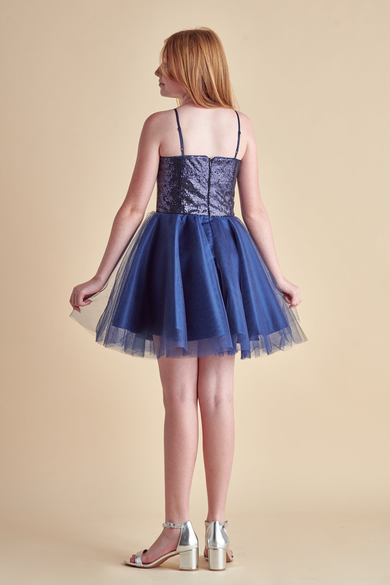 Red haired girl in a navy sequin bodice dress with full tulle skirt and silver shoe.