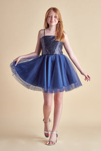 Red haired girl in a navy sequin bodice dress with full tulle skirt and silver shoe.