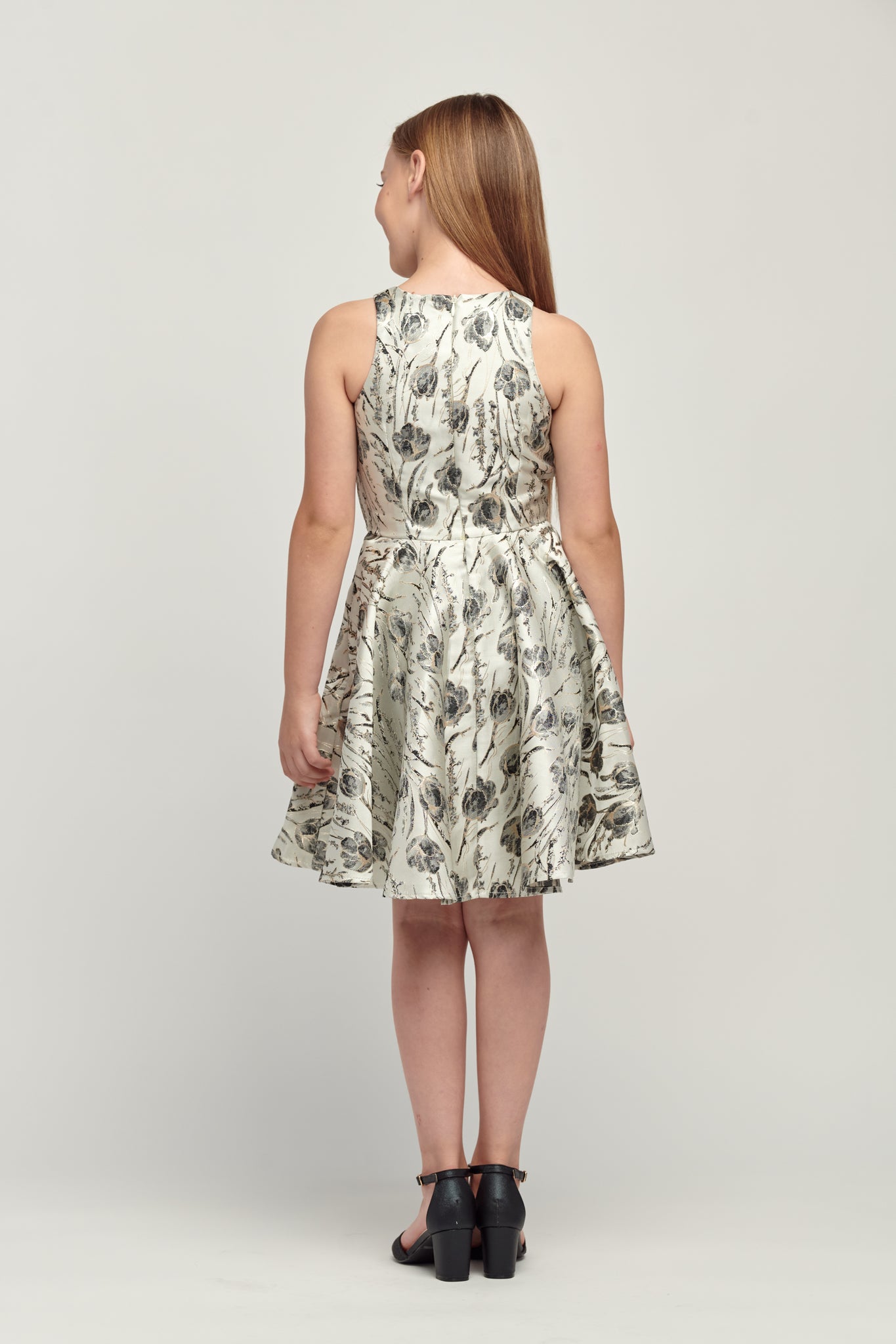 Back of black and silver floral jacquard racerback dress in longer length featuring a high neckline, high waist detailing and full circle skirt. This dress can be worn with a sports bra as the back covers most of the back.