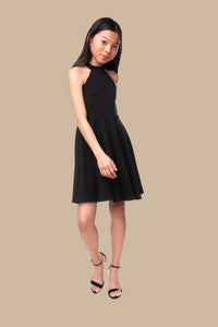 Halter dress in black features a full circle twirl skirt, open hole detailing in back and high waist line for a chic silhouette.