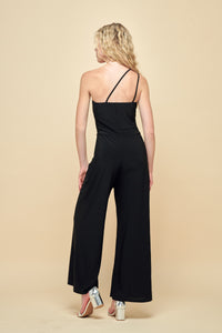 Blonde girl in a one shoulder, wide leg jumpsuit with silver heel.