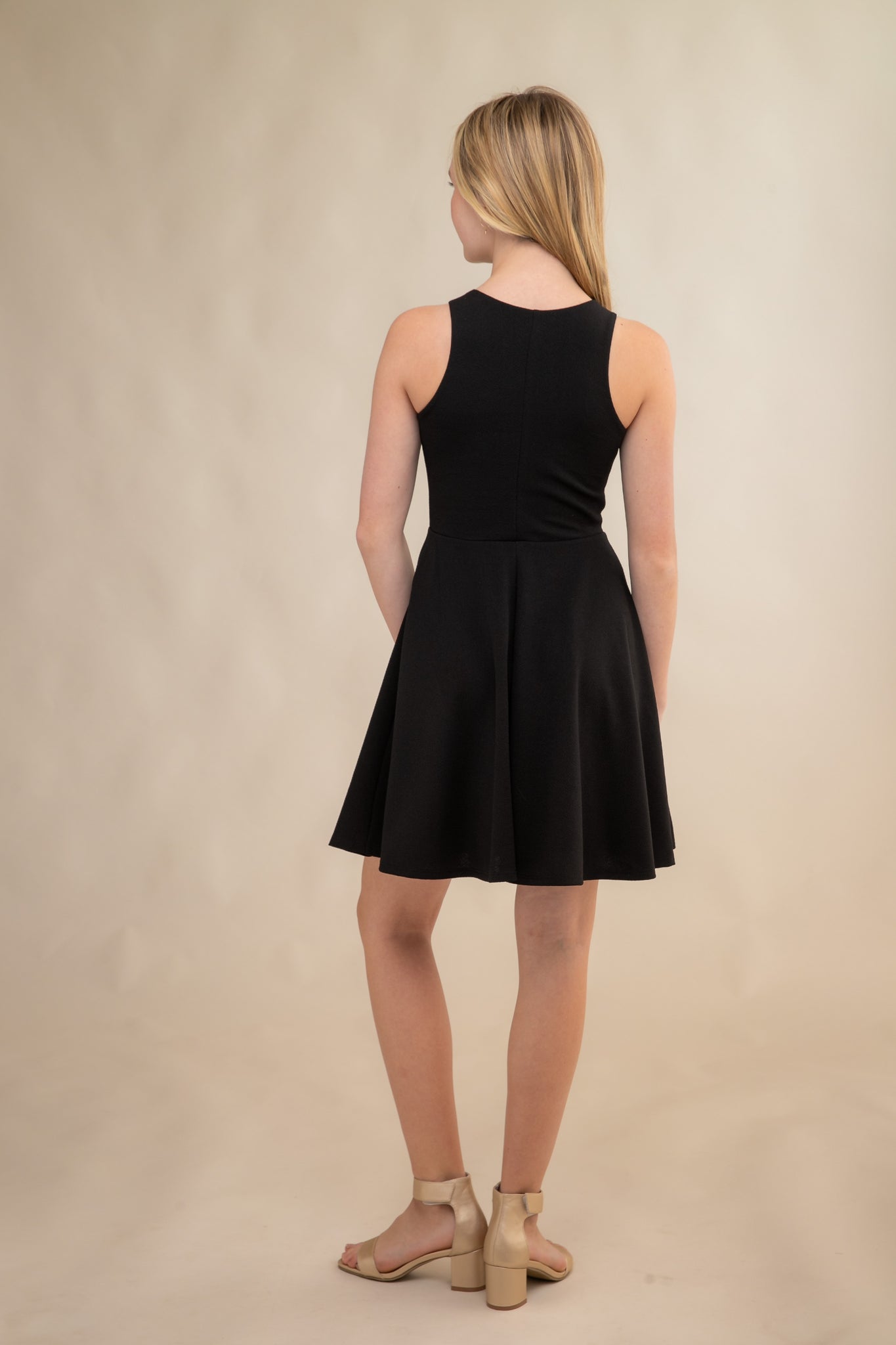 The tank style sleeve textured fit and flare dress is shown in black with high neck line, racerback detailing and dart bodice for a chic and sophisticated look. This dress can be worn to a more conservative special occasion event like cotillion, graduation, or religious service like a bat mitzvah service or church ceremony.