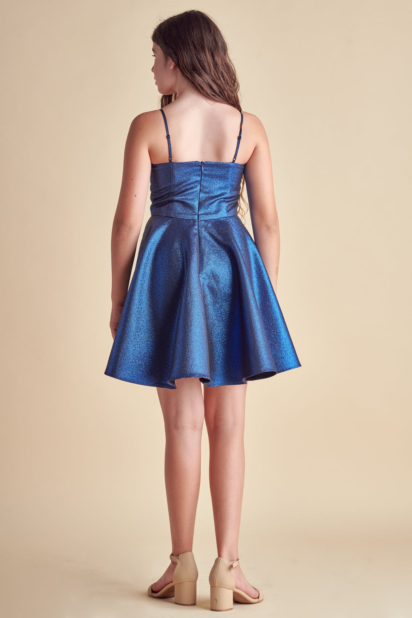 This is an all over non-stretch, glitter fabric dress made in a longer length in cobalt blue. It hits right above the knee and features a full circle skirt.