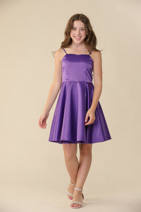 Brown haired girl wearing rich, purple satin party dress hitting above the knee with a sparkle heel shoe.