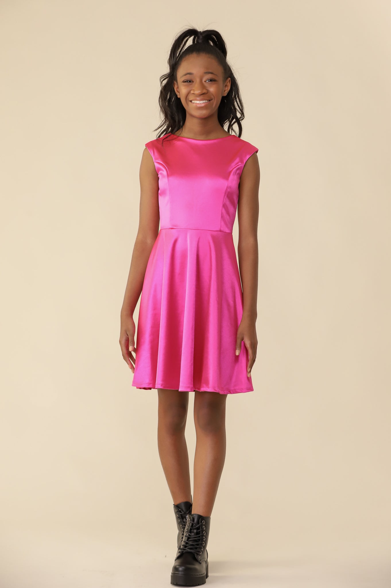 The cap sleeve satin fit and flare dress is shown in fuchsia with high neck line, shoulder coverage and lower v-back detailing for a chic and sophisticated look. This dress can be worn to a more conservative special occasion event like cotillion, graduation, or religious service like a bat mitzvah service or church ceremony.