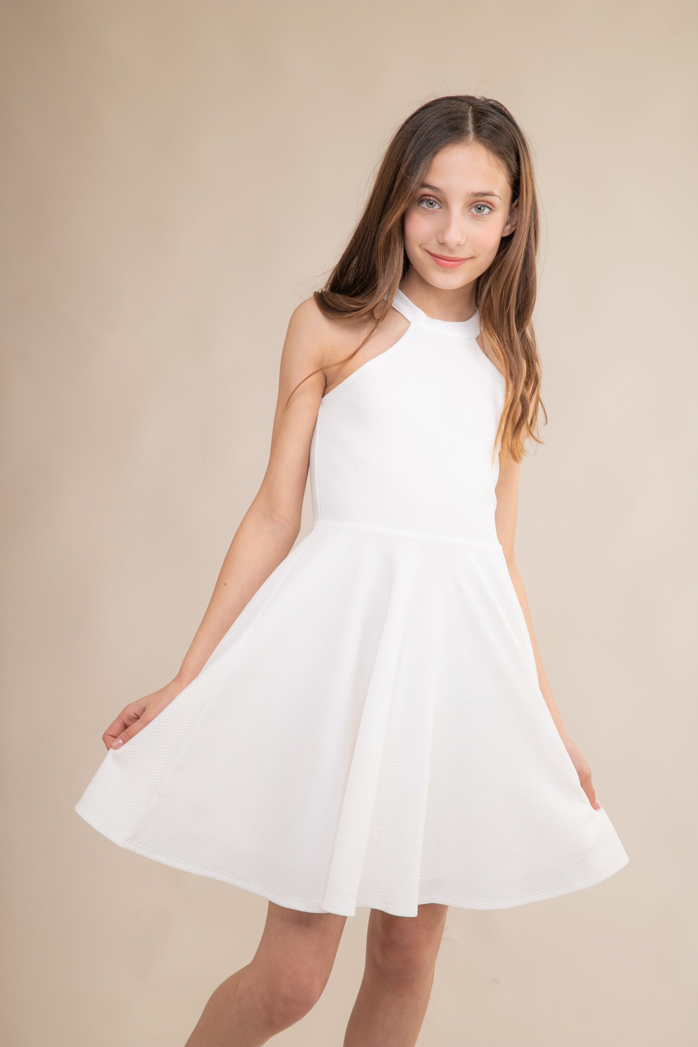 Halter dress in ivory features a full circle twirl skirt, open hole detailing in back and high waist line for a chic silhouette.